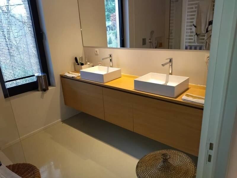 Badkamer met dubbele lavabo en houten meubel, net schoongemaakt