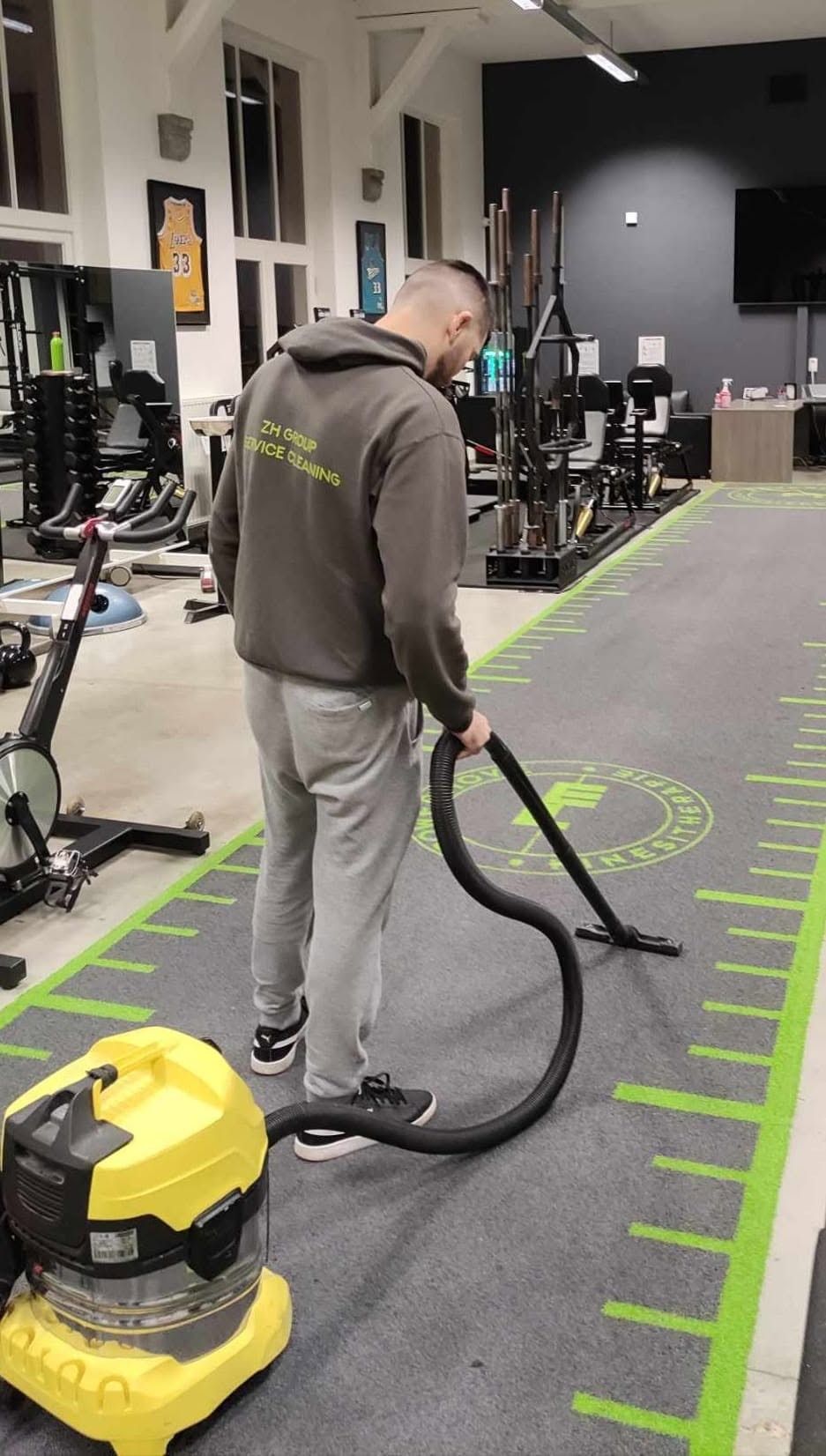 Medewerker van ZH Group stofzuigt de vloer van een sportzaal